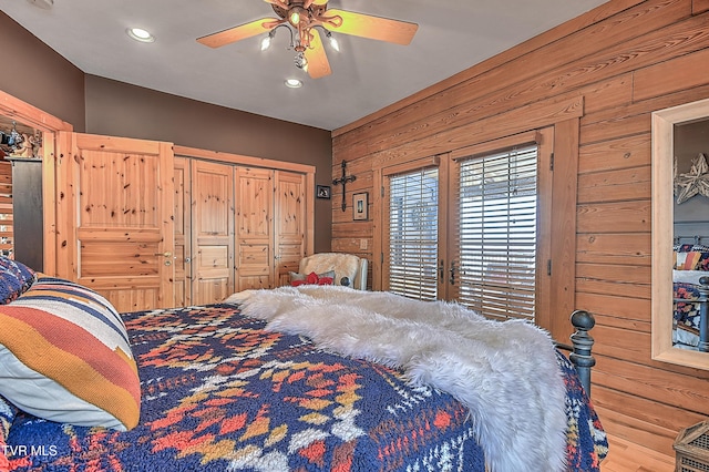 bedroom featuring ceiling fan and wood walls