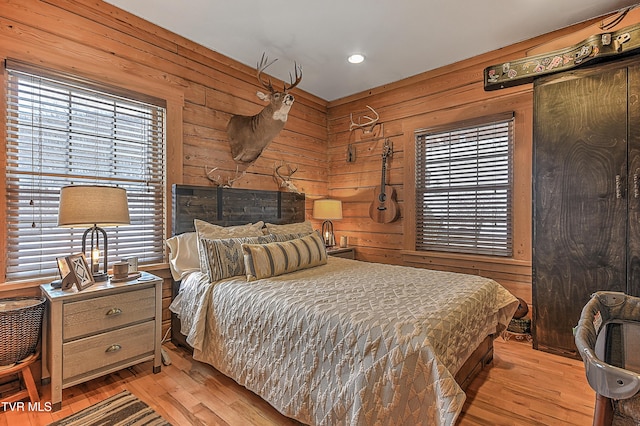 bedroom with light hardwood / wood-style flooring and wood walls