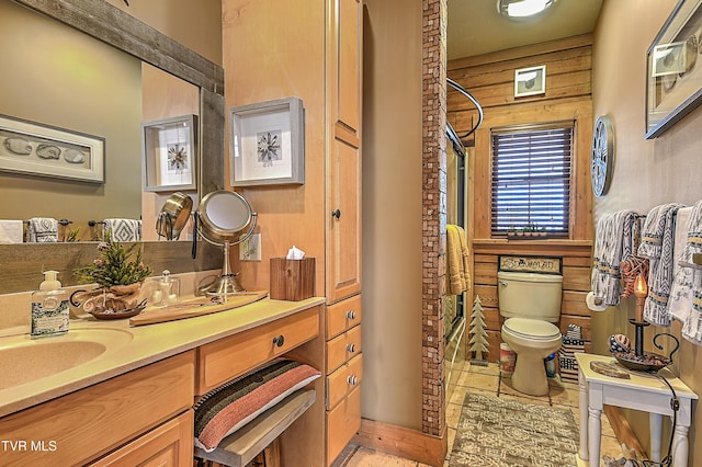 bathroom with vanity, toilet, and wood walls