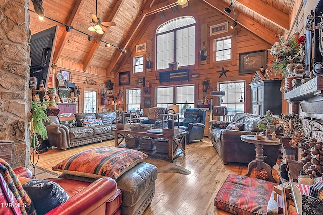 living room featuring wood walls, wood ceiling, hardwood / wood-style flooring, ceiling fan, and beam ceiling