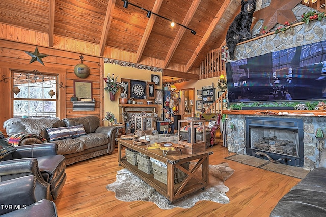 living room with beam ceiling, light wood-type flooring, wooden ceiling, and a fireplace