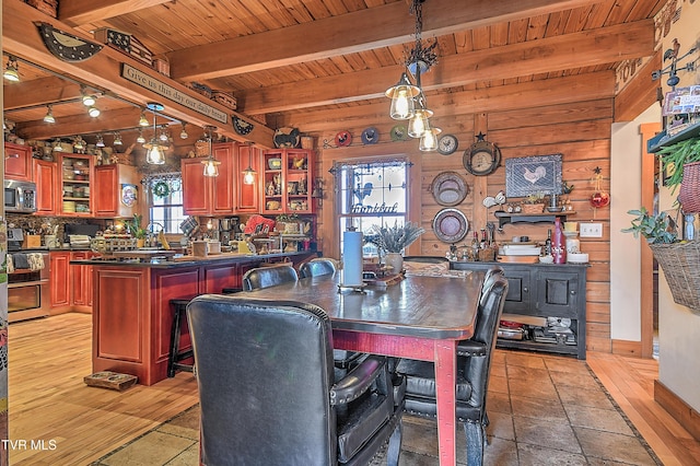 dining space with beamed ceiling, wood ceiling, wooden walls, and light wood-type flooring