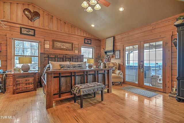 bedroom featuring french doors, high vaulted ceiling, light hardwood / wood-style flooring, wooden walls, and access to exterior