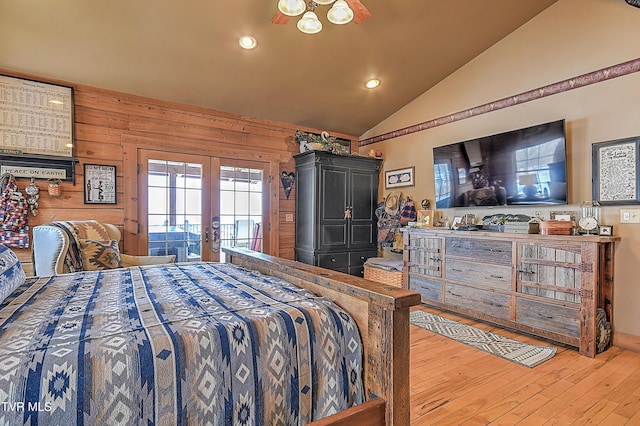 bedroom with french doors, vaulted ceiling, access to outside, wooden walls, and hardwood / wood-style floors