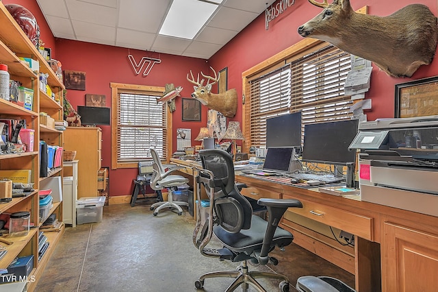 home office with concrete flooring and a paneled ceiling