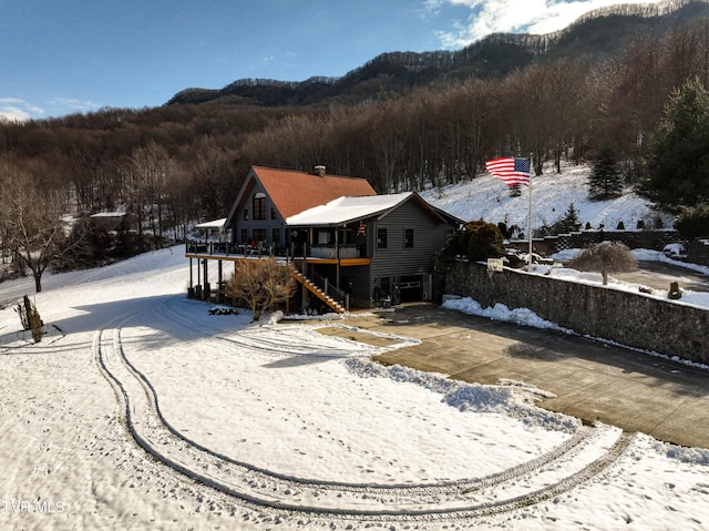 snow covered property with a mountain view and a garage