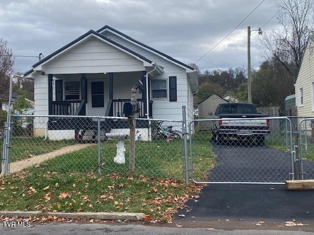 bungalow-style home featuring driveway, a fenced front yard, covered porch, a gate, and a front yard