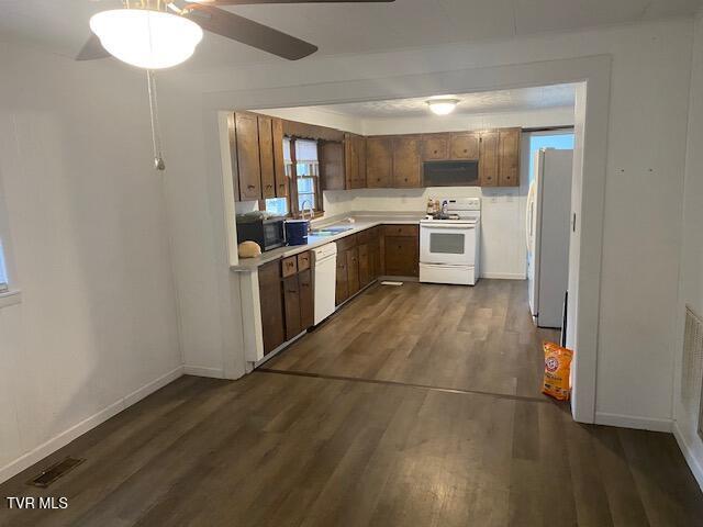 kitchen featuring white appliances, baseboards, brown cabinets, dark wood-type flooring, and light countertops