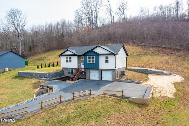 view of front of house with a garage, central air condition unit, and a front lawn