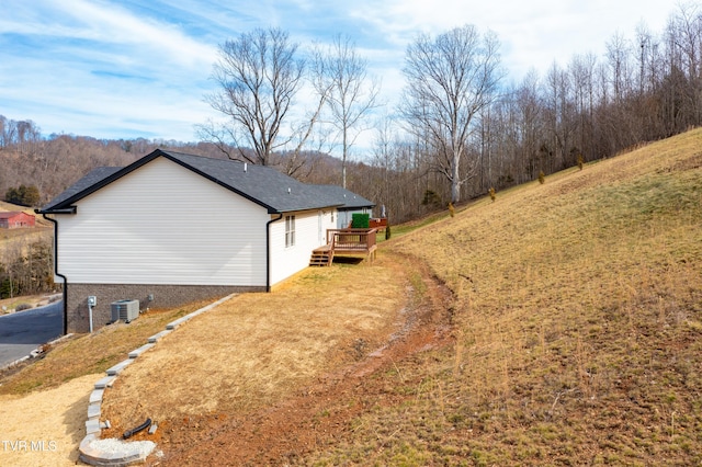 view of side of property with central AC unit, a yard, and a deck