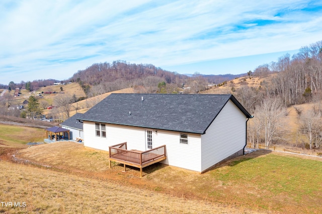 rear view of house featuring a deck and a lawn