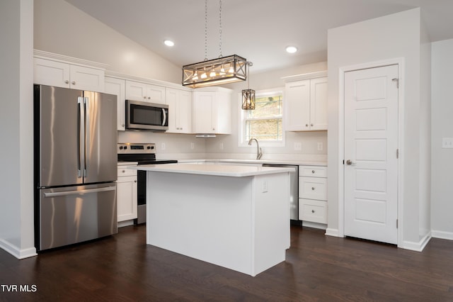 kitchen with a kitchen island, appliances with stainless steel finishes, pendant lighting, and white cabinets