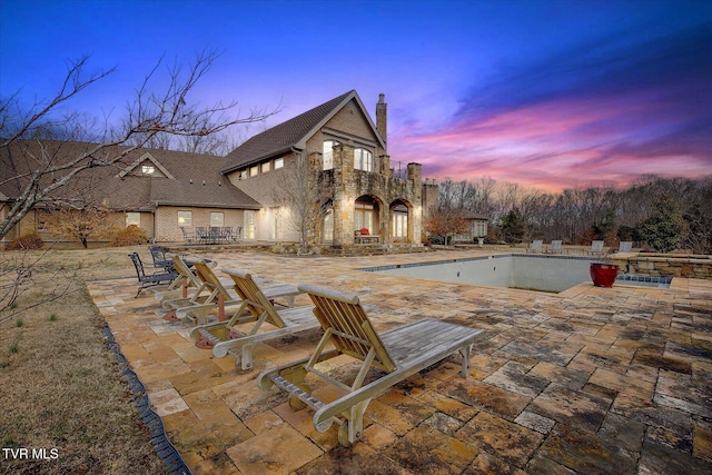 patio terrace at dusk featuring an empty pool