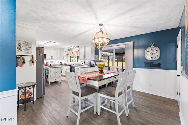 dining room with dark hardwood / wood-style floors, a textured ceiling, and a notable chandelier