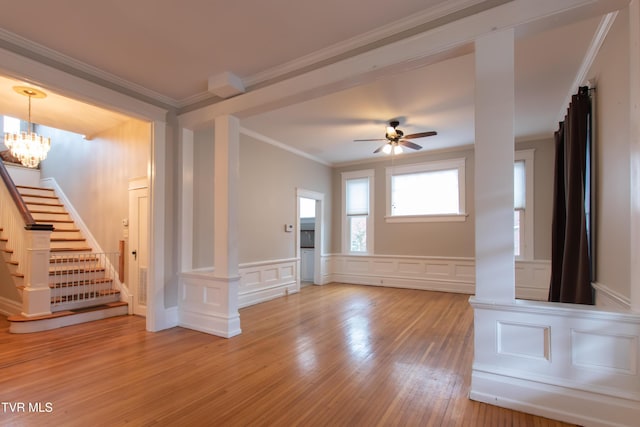 unfurnished living room with crown molding, ceiling fan with notable chandelier, and hardwood / wood-style floors