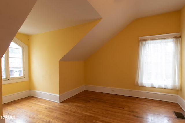 additional living space with wood-type flooring and vaulted ceiling