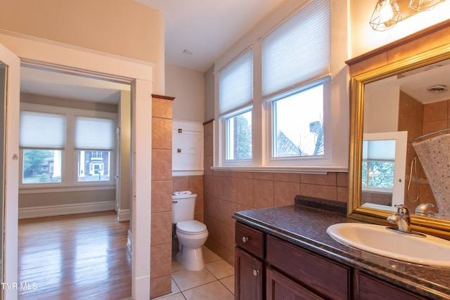 bathroom with curtained shower, tile walls, vanity, toilet, and tile patterned floors