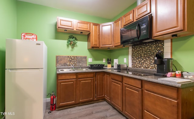 kitchen featuring sink, backsplash, black appliances, and light hardwood / wood-style floors