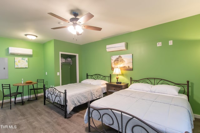 bedroom with wood-type flooring, a wall mounted air conditioner, ceiling fan, and a closet