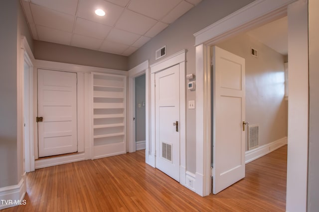 hall with a paneled ceiling and light hardwood / wood-style floors