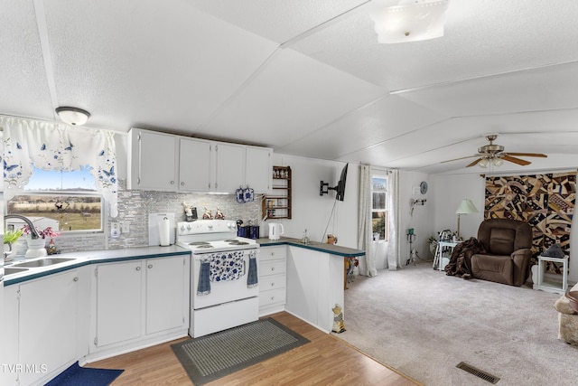 kitchen featuring white electric stove, lofted ceiling, a sink, visible vents, and open floor plan