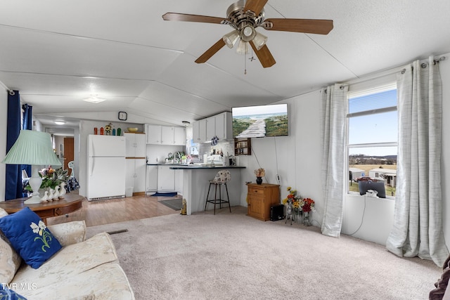 living room featuring lofted ceiling, light colored carpet, ceiling fan, and visible vents