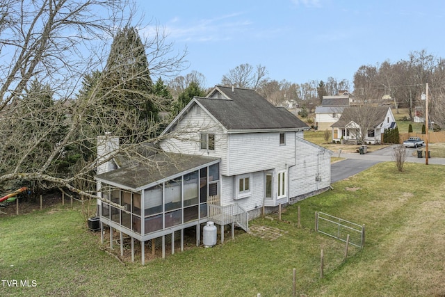 back of house with a sunroom and a lawn