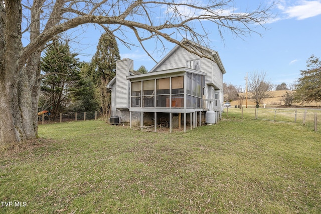 rear view of property featuring a sunroom, central AC, and a lawn