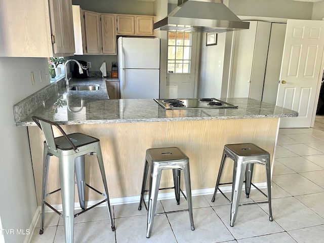 kitchen with white refrigerator, a breakfast bar, sink, and exhaust hood