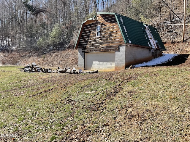 view of side of home with a garage, metal roof, a lawn, and a gambrel roof