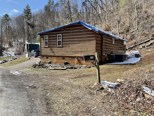 view of property exterior featuring crawl space, driveway, and cooling unit