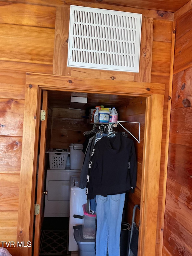 details featuring wood walls, visible vents, and washer and dryer