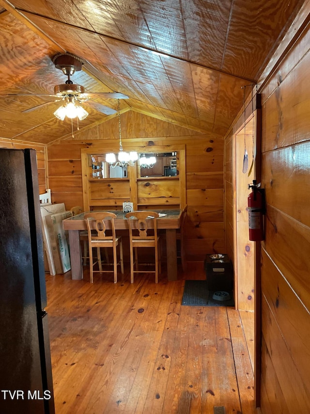 unfurnished dining area with lofted ceiling, wood walls, wooden ceiling, and wood finished floors