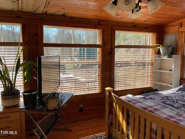 bedroom featuring vaulted ceiling, wood walls, wooden ceiling, and wood finished floors