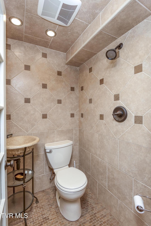 bathroom featuring a tile shower and toilet