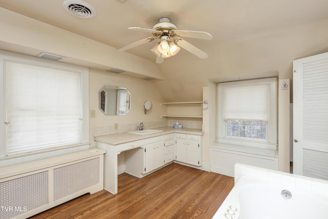 bathroom with lofted ceiling, radiator, a bathtub, a wealth of natural light, and hardwood / wood-style flooring