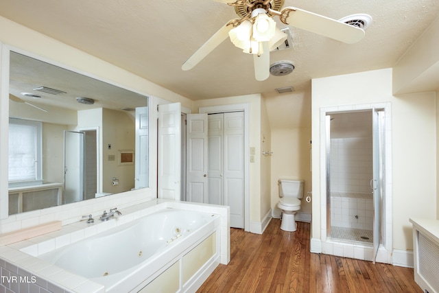 bathroom featuring plus walk in shower, radiator heating unit, hardwood / wood-style flooring, ceiling fan, and toilet