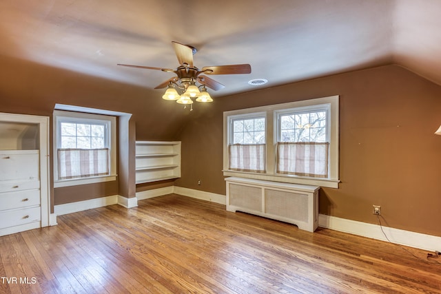 additional living space featuring lofted ceiling, radiator, light hardwood / wood-style flooring, and plenty of natural light