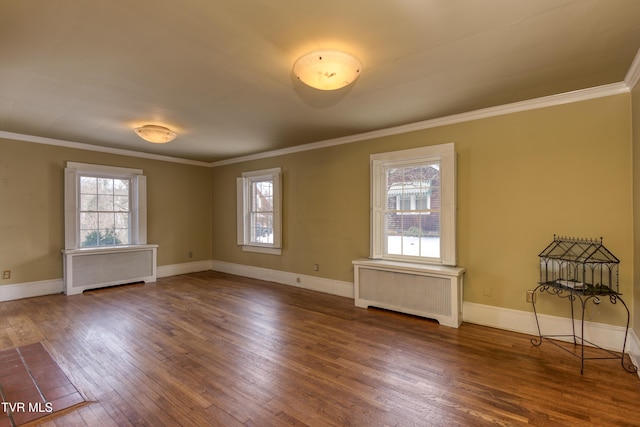 empty room with hardwood / wood-style flooring, radiator heating unit, and a wealth of natural light