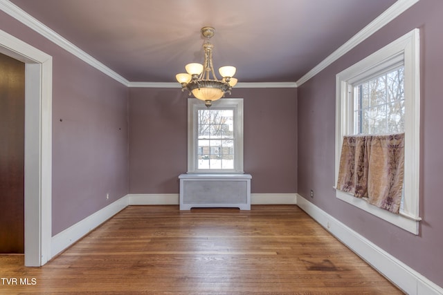 unfurnished dining area with ornamental molding, wood-type flooring, and a notable chandelier