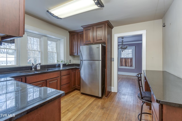 kitchen with a healthy amount of sunlight, sink, stainless steel fridge, and light hardwood / wood-style flooring