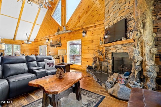 living room featuring a stone fireplace, wood walls, a chandelier, high vaulted ceiling, and hardwood / wood-style flooring