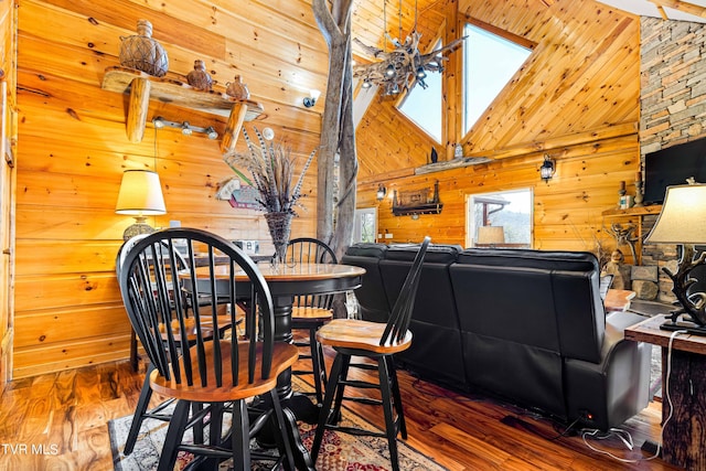 dining room featuring dark wood-type flooring, wooden walls, and high vaulted ceiling