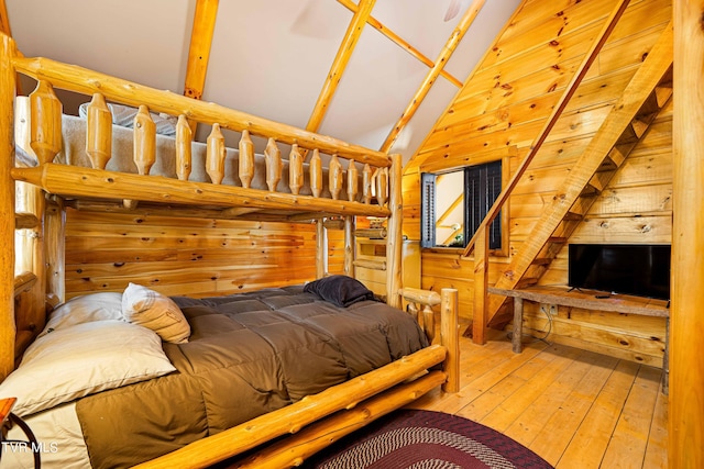 bedroom with vaulted ceiling, hardwood / wood-style floors, and wooden walls