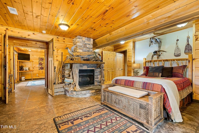 bedroom featuring wood ceiling, a stone fireplace, and wood walls