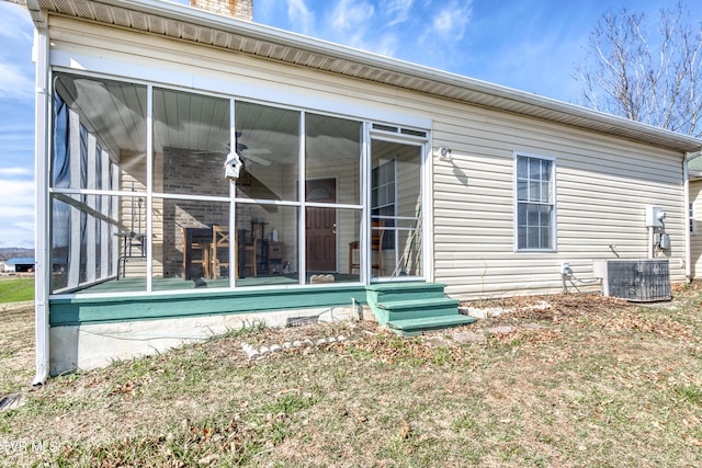 rear view of house featuring central AC, a sunroom, and a lawn