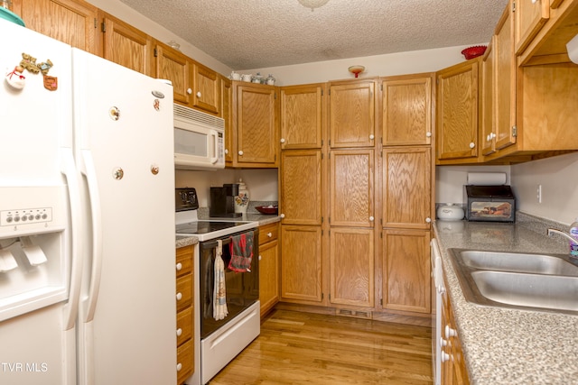 kitchen featuring sink, a textured ceiling, white appliances, and light hardwood / wood-style floors