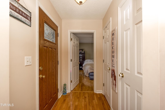 hall featuring light hardwood / wood-style flooring and a textured ceiling