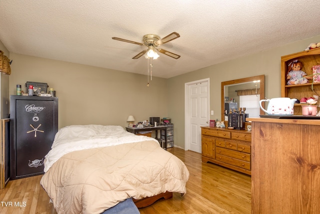 bedroom with ceiling fan, a textured ceiling, and light wood-type flooring