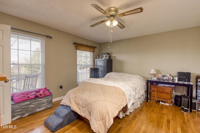 bedroom featuring ceiling fan, light hardwood / wood-style floors, and a textured ceiling